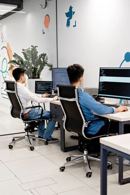services-01 Dual monitors on a desk, showcasing web design in a modern office setting.